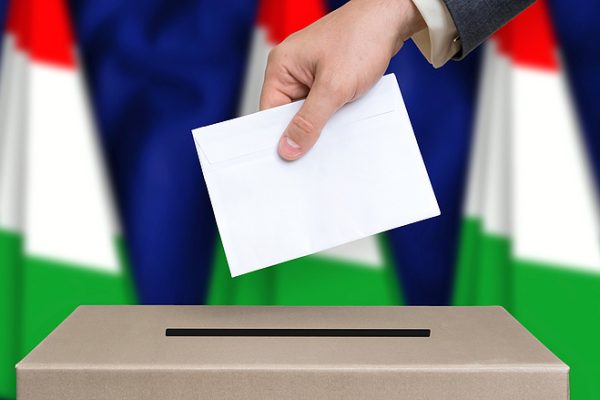 férfi kéz szavazólapot dob egy urnába